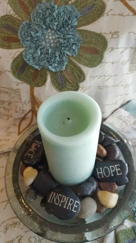 A candle sitting on top of rocks with hope written on it.