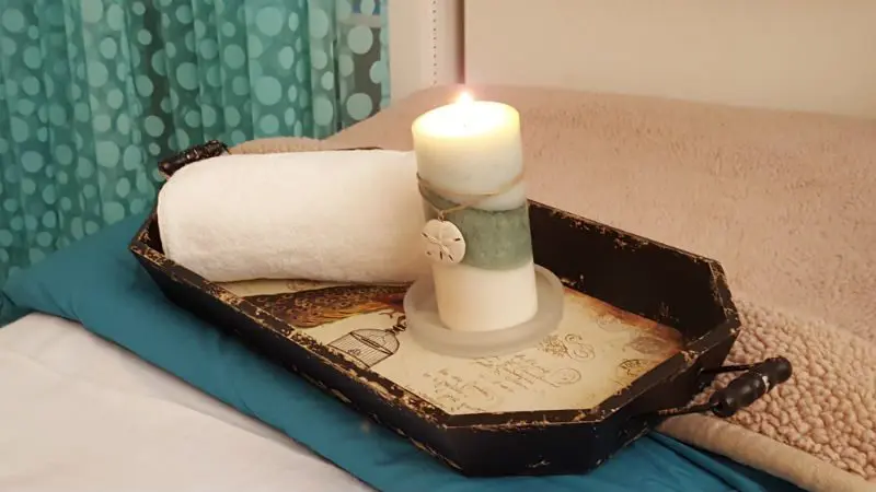 A candle is lit on the table in the bathroom.